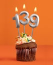 Birthday cupcake with number 139 candle - Orange color background Royalty Free Stock Photo