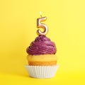 Birthday cupcake with number five candle on yellow Royalty Free Stock Photo