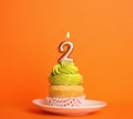 Birthday cupcake with number two candle in  on orange background Royalty Free Stock Photo