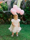 Birthday of baby girl with air balloons in outdoor garden. Happy child in dress Royalty Free Stock Photo