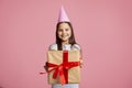 Birthday gift. Happy little girl in cap with present box with red ribbon Royalty Free Stock Photo