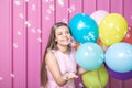 Portrait of beautiful young woman with colorful balloons and soap bubbles on pastel pink background. Royalty Free Stock Photo