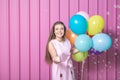 Birthday girl with balloons and soap bubbles against rose metal wall. Royalty Free Stock Photo