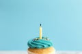 Birthday greeting concept. Blown out candle on muffin, cupcake. Blue background