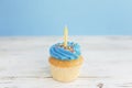 Birthday greeting concept. Yellow candle on muffin, cupcake. Blue background