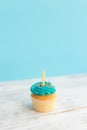 Birthday greeting concept. Yellow candle on muffin, cupcake. Blue background Royalty Free Stock Photo