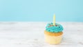 Birthday greeting concept. Yellow candle on muffin, cupcake. Blue background Royalty Free Stock Photo