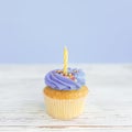 Birthday greeting concept. Yellow candle on muffin, cupcake. Blue background Royalty Free Stock Photo