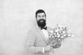 Birthday greetings. Best flowers for girlfriend. Flowers for her. Man bearded suit bow tie hold tulips bouquet Royalty Free Stock Photo