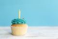 Birthday greeting concept. Yellow candle on muffin, cupcake. Blue background Royalty Free Stock Photo