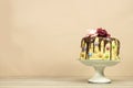 Birthday layer cake decorated with chocolate pieces and happy birthday text, hazelnuts and roses flowers on wood table