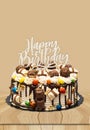 Birthday layer cake decorated with chocolate pieces with happy birthday text on wooden board