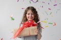 Birthday. Little beautiful girl in a white dress with her hair stands at the window. She smiles. In her hands is a box Royalty Free Stock Photo