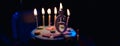 Birthday cake with burning candles and age 6 candle in the dark background with candies in decor Royalty Free Stock Photo