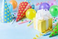 Birthday party background with gift box, colorful balloons, confetti, carnival cap and streamer. Holiday supplies on table Royalty Free Stock Photo