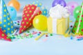 Birthday party background with gift or present box, colorful balloons, confetti, carnival cap and streamer. Holiday supplies