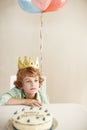 Birthday party, cake and balloons with sad boy by table in family home for celebration, growth and lonely. Dessert Royalty Free Stock Photo
