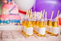 Birthday party concept, candy bar for children. A lot of bottles of apple juice, special labels on it, white and yellow straws,