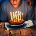 Birthday and party event by night concept - cake and candles on a wooden table - unrecognizable people ready to blow the fire and