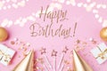 Birthday party festive pink background with golden decoration from gift, balloons, hat, candles, confetti, candy and streamers Royalty Free Stock Photo