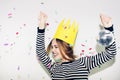 Birthday party, new year carnival. Young smiling woman on white background celebrating brightful event, wears stripped Royalty Free Stock Photo