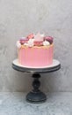 Birthday pink cake for a little girl with fondant crown, melted chocolate, meringue and cake pops on grey background