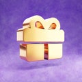 Birthday present icon. Gold glossy gift symbol isolated on violet velvet background.