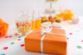 Birthday present in orange wrap on table at party