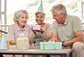 Birthday, senior friends with cake and gift for celebration in living room, smile and candles in retirement. Happiness Royalty Free Stock Photo