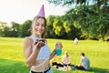 Birthday, teenage girl in festiv hat with cake and candle at outdoor party