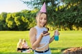 Birthday, teenage girl in festiv hat with cake and candle at outdoor party