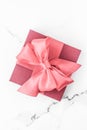 Coral gift box with silk bow on marble background, girl baby shower present and glamour fashion gift for luxury beauty brand, Royalty Free Stock Photo