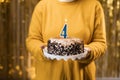 Birthday 4. Woman holding birthday cake with burning candles number 4 against decorated background, close up. Celebrates