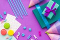 Birthday wrapped gifts and party hats on purple background top view