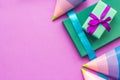 Birthday wrapped gifts and party hats on purple background top view copyspace
