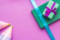 Birthday wrapped gifts and party hats on purple background top view copyspace