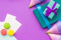 Birthday wrapped gifts and party hats on purple background top view copyspace