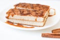 Biscuit cake with caramel syrup on white plate with cinnamon sticks on wooden background, Royalty Free Stock Photo