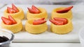 Biscuit cakes with fresh berries, chocolate, and whipped heavy cream. Woman preparing dessert, mini biscuit cups with strawberries