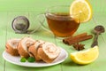 Biscuit swiss roll with a cup of tea on green wooden background