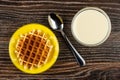 Biscuit waffle in saucer, spoon, transparent bowl with condensed milk on table. Top view Royalty Free Stock Photo