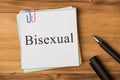 Bisexuality concept. Photo above of notes with paperclips and pen isolated on the wooden background