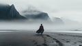 Mysterious Cloaked Man Walking On Beach Near Mountain In The Fog