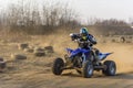 ATV racer takes a turn during a race on a dusty terrain. Royalty Free Stock Photo