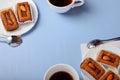 Bisquit cakes and coffee or tea cups on blue background