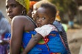 Portrait of a baby daughter being carried on her mother shoulders, at the Bissaque neighborhood in the city of Bissau
