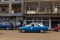 Street scene in the city of Bissau with a taxi and people in front of a crumbling building, in Guinea-Bissau