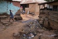 Young girl walking on a dirt street in a slum with an open air sewer, at the city of Bissau