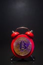 Bitcoin and alarm clock on black background. Deadline concept for investing in bitcoin cryptocurrency. Royalty Free Stock Photo
