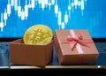 Bitcoin BTC cryptocurrency in a gift box with a stock trading background, gold coin as a symbol of electronic virtual money Royalty Free Stock Photo